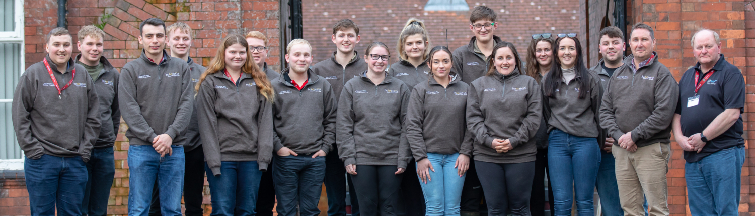 The full cohort of sixteen delegates, including Reaseheath’s own farm team members Lucy Szolkowska and Drew Gerry, stand together outside the college. These young leaders represent the future of professional dairy farming.