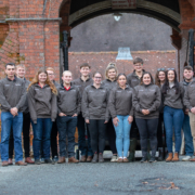 The full cohort of sixteen delegates, including Reaseheath’s own farm team members Lucy Szolkowska and Drew Gerry, stand together outside the college. These young leaders represent the future of professional dairy farming.