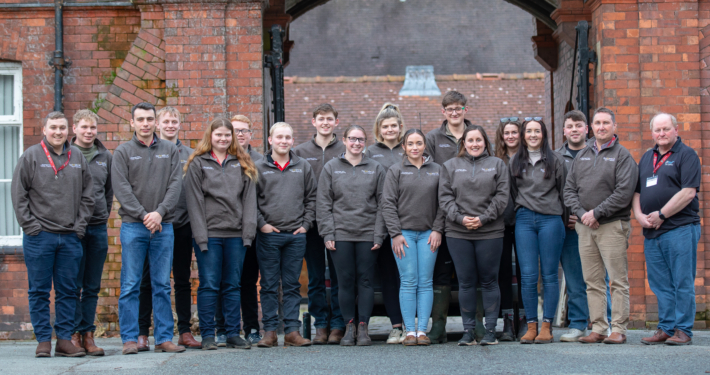 The full cohort of sixteen delegates, including Reaseheath’s own farm team members Lucy Szolkowska and Drew Gerry, stand together outside the college. These young leaders represent the future of professional dairy farming.