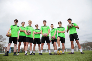 A group of Reaseheath Men’s 1st Team football players in their team kit, standing together on the training pitch ahead of the Cheshire County Cup Final.