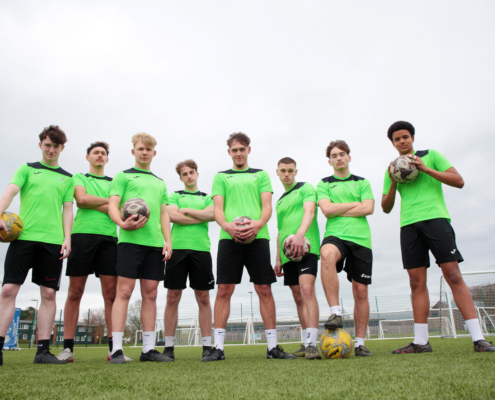 A group of Reaseheath Men’s 1st Team football players in their team kit, standing together on the training pitch ahead of the Cheshire County Cup Final.